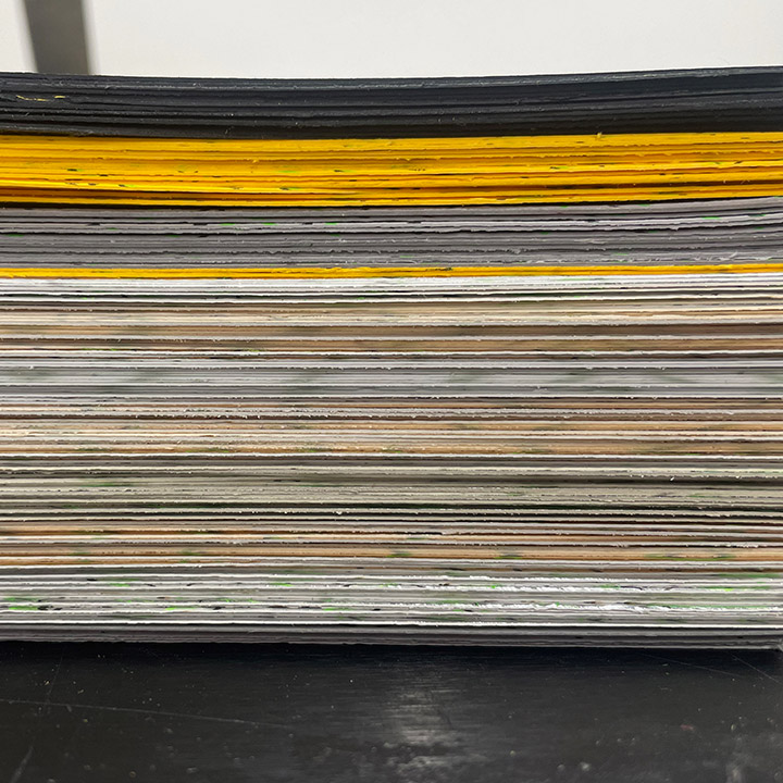 Side view of pile of different printed cards on different stocks